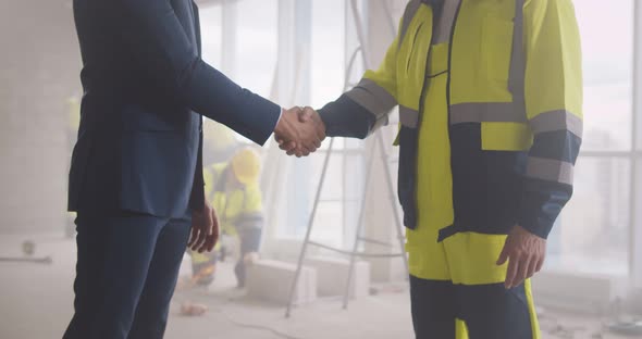 Cropped Shot of Businessman and Builder Shaking Hands at Construction Site alt