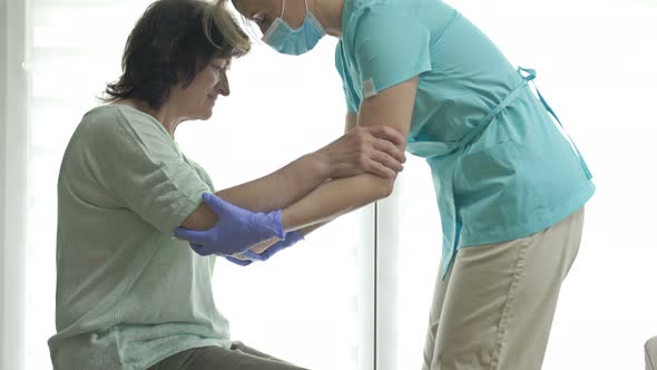 Doctor or Nurse is Helping an Elderly Woman to Get to Her Feet alt