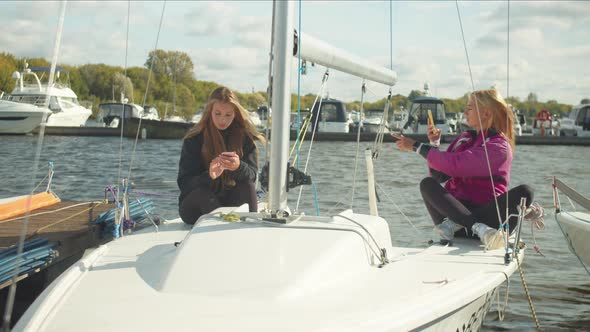 Young Girls with Smartphones Sit on Board an Expensive Sports Yacht and Take Selfies for Their Video