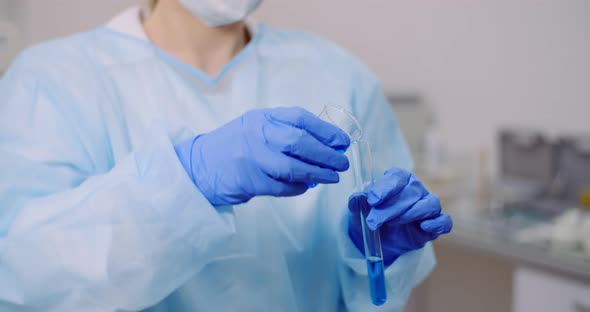 Female Scientist Holding Tubes and Flask with Liquid in Hands alt