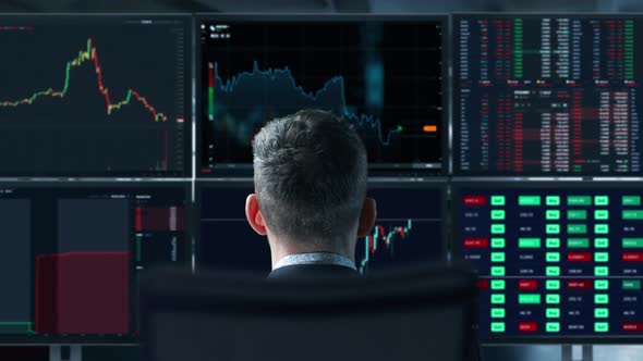 Trader is Working with Multiple Computer Screens Full of Charts and Data Analysis and Stock Broker alt