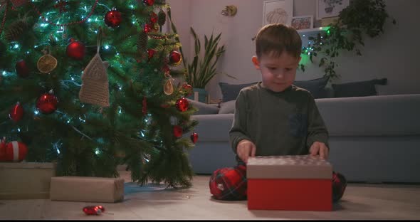 Happy Smiling Little Boy Opens His Christmas Gift From Santa Claus alt