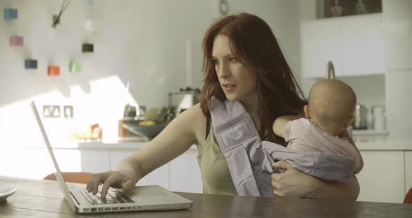 Mother with her daughter using laptop in kitchen