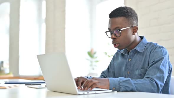 Positive Young African Man Celebrating Success on Laptop alt