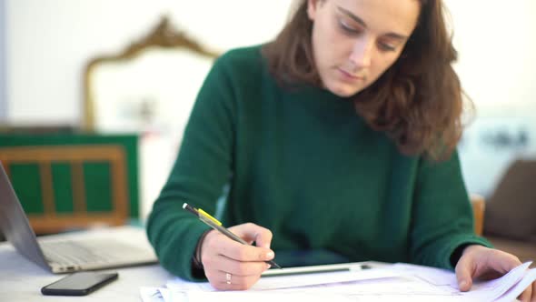 Young woman looking at laptop computer while working on project alt