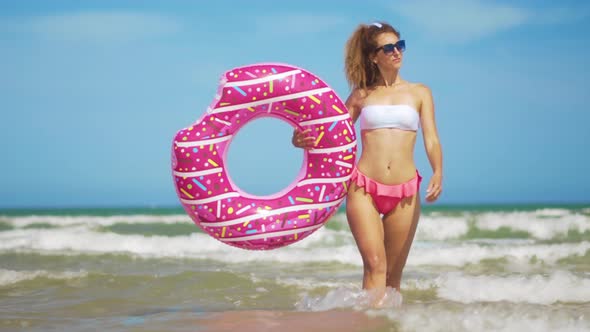 Young Woman Having Fun with Toy Inflatable Ring Donut on the Beach alt