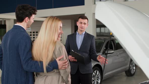 Auto Business Professional Car Sales Manager Advises Female and Male Buyers About New Vehicle Model