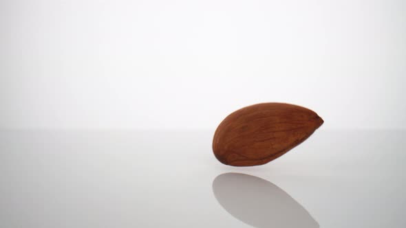 Camera follows a single almond falling on surface. Slow Motion. alt