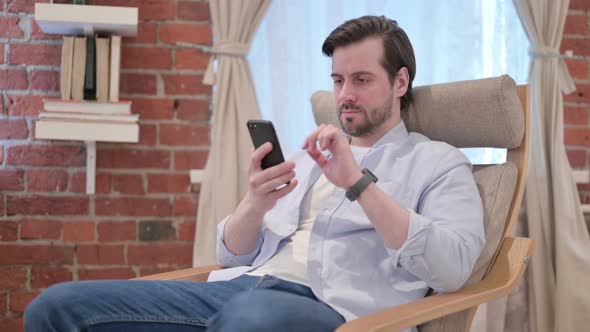 Casual Young Man Using Smartphone on Sofa alt