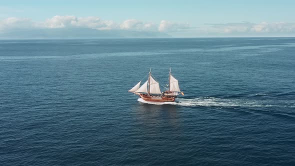 A Lone Sailboat with White Sails Glides Over the Waves on the Open Sea in Clear Weather with a alt