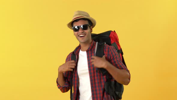 Smiling Indian male tourist backpacker walking waving and giving thumbs up
