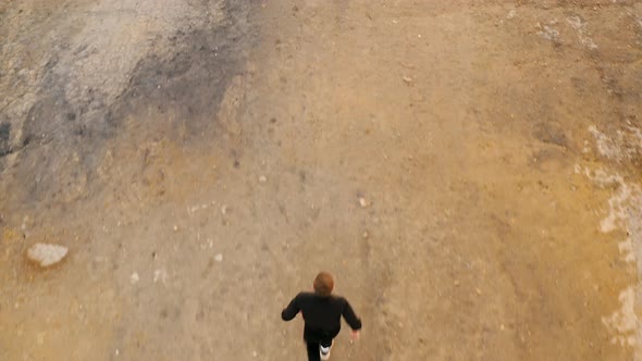 Man running uphill Ural Mars Desert Rear view of fit young man jogging in dry desert at sunrise alt