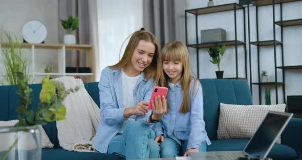 Sisters Having Fun Together while Spending Joint Leisure at Home Watching Funny Videos alt