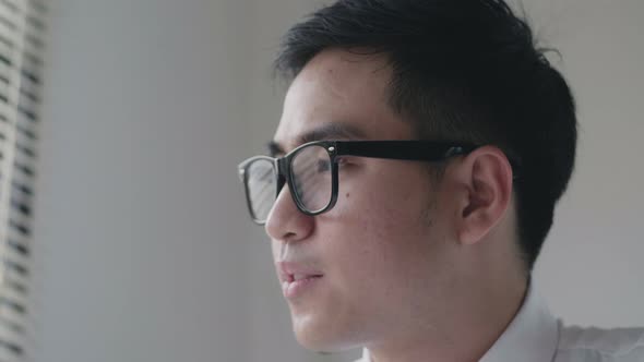 Asian businessman feeling tired and looking outside the window.