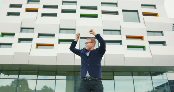 The Businessman Is Happily Dancing and Standing Near the Business Center alt