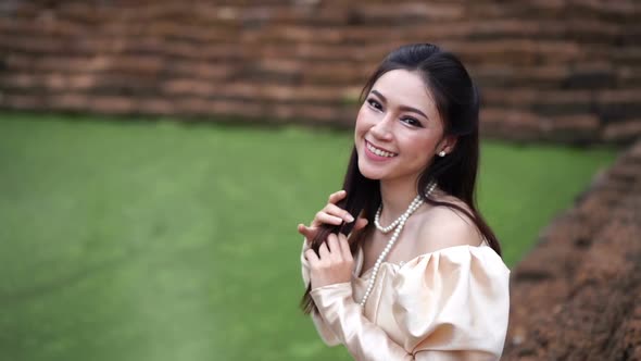 slow motion of happy beautiful woman in Thai traditional dress near the pond alt