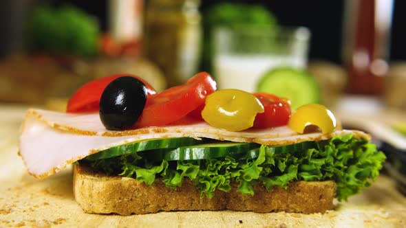 Delicious fresh sandwich preparation with cucumber, olives, ham, tomatoes and green lettuce