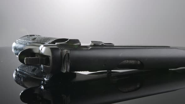 Gun Control. Studio shot of a 9mm gun rotating on a reflective surface