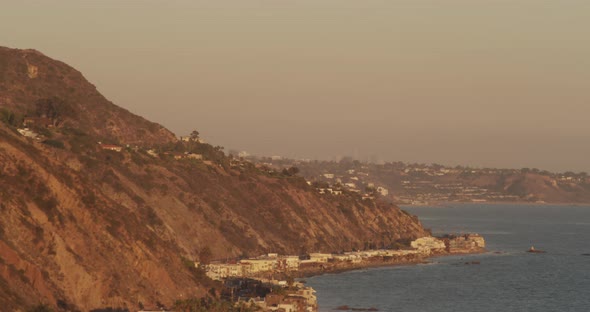 Helicopter aerial birds eye view shot moving down where shore meets PCH highway, sundown