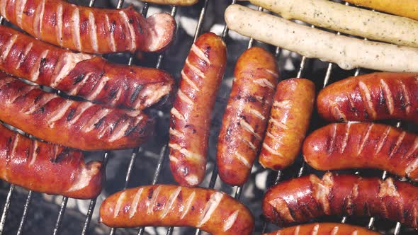 Brats Being Cooked on a Grill with Flame and Smoke alt