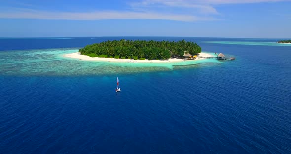 Aerial drone view of a man and woman sailing on a boat to a tropical island. alt