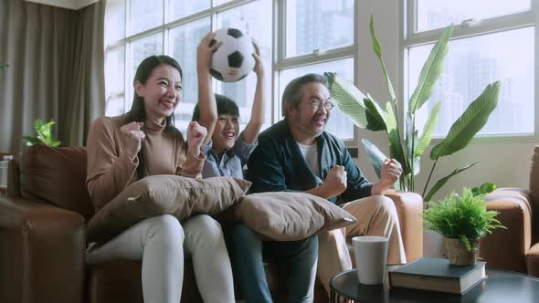 Asian parents And Son Watching Sports On TV Cheering Favorite Soccer Team
