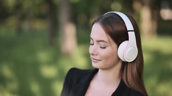 A Girl Wearing Headphones Listening to Music in a City Park alt
