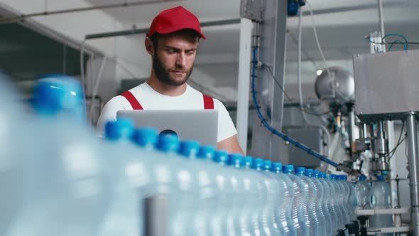 Young Man Worker of Water Factory Checking Quality and Making Inspection in Line Production