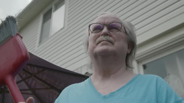 Man holding broom looking back and fourth alt