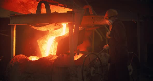 Foundry, a man pours molten metal into the mold