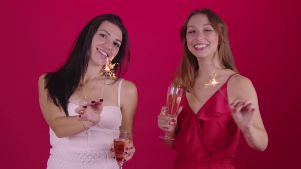 Two Cheerful Women with Sparklers Champagne Dancing Celebrating Xmas Holiday