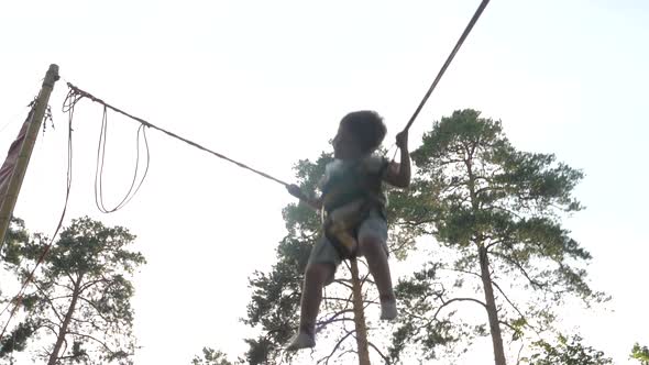 Little Child Jump on theTrampoline with Elastic Ropes. Happy Boy Is Flying Up To the Sky. Baby alt