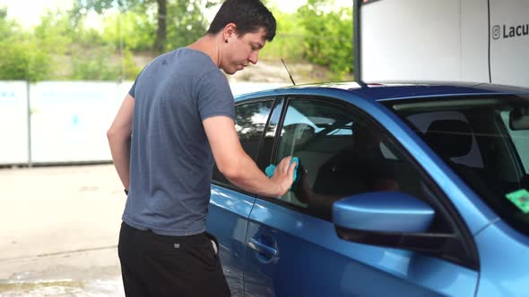 Man Cleaning Car and Drying Vehicle with Microfiber Cloth alt