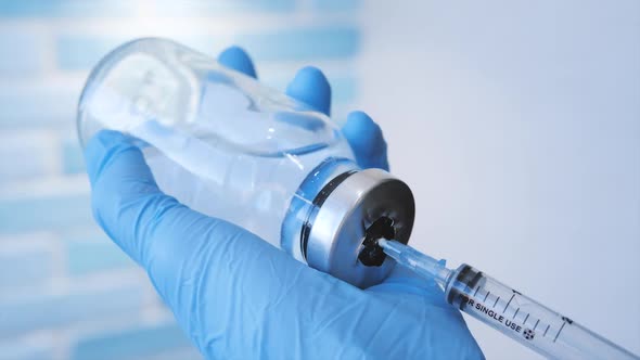 A Doctor or Nurse in Blue Medical Gloves Dials Medicine Into a Syringe alt