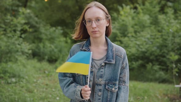 Portrait of a Woman 20s 30s Activist with the Flag of Ukraine Outdoors Llooks at the Camera