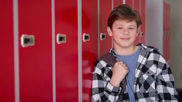 Video portrait of smiling teenager standing in corridor near lockers. alt