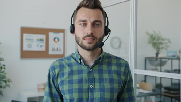 Slow Motion Portrait of Handsome Guy Wearing Headphones with Microphone Standing in Office alt