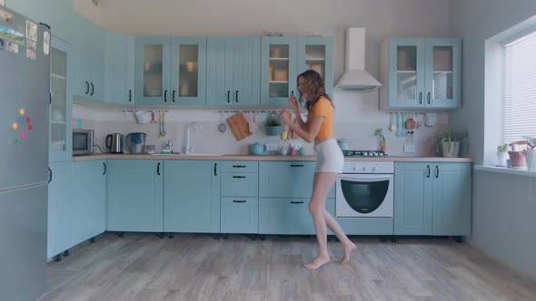 A Beautiful Woman in White Shorts is Relaxing at Home Dancing in the Kitchen alt