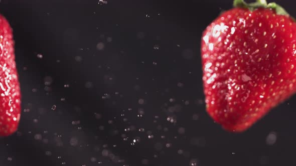 Two Big Strawberries are Flying and Colliding on a Black Background alt
