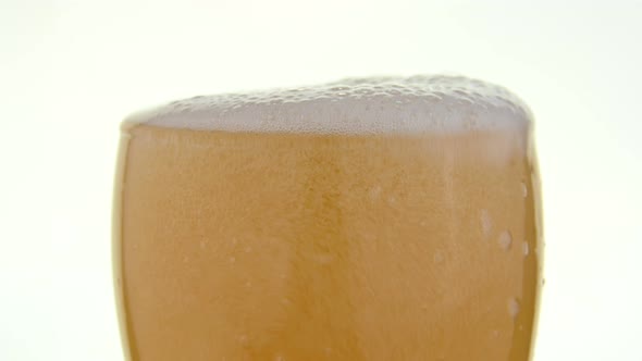 Close up pouring lager beer in glass over white alt