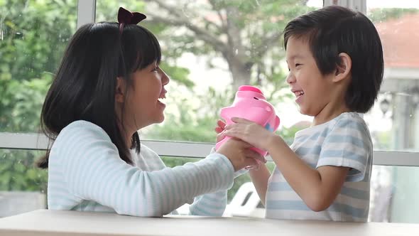 Cute Asian Child Putting A Coin In To A Piggy Bank Slow Motion alt