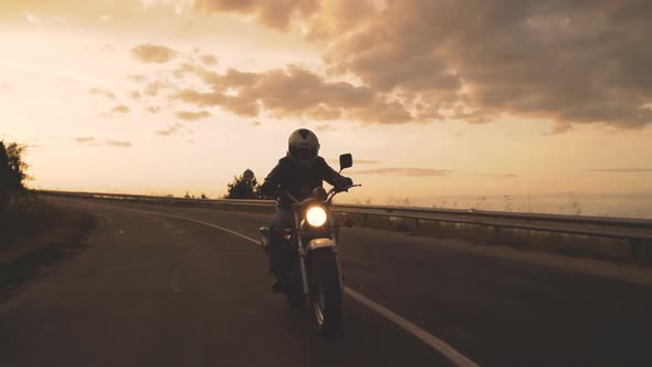 Motorcyclist Enjoys a Ride on His Motorbike at Sun Dawn on the Road to Freedom alt