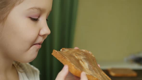 Teenage Preschooler Girl Eating Chocolate Butter Sandwich and Smiling