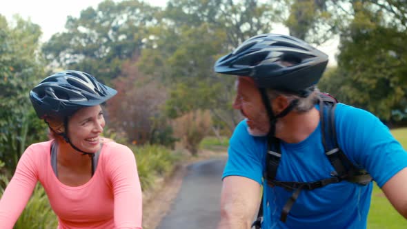 Couple interacting face to face while riding bicycle alt