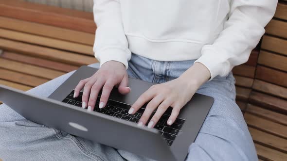 Young Female in Garden Using Laptop Communicates on Internet with Customer