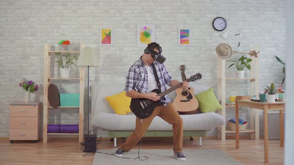 Young Man Musician in Virtual Reality Glasses Emotionally Playing the Electric Guitar alt