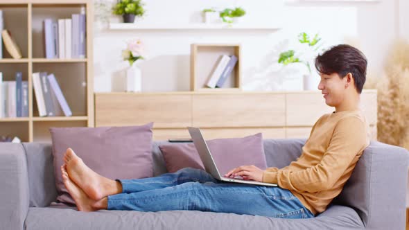 Entrepreneur handsome business asian man wear shirt lying on couch working online with computer lapt alt