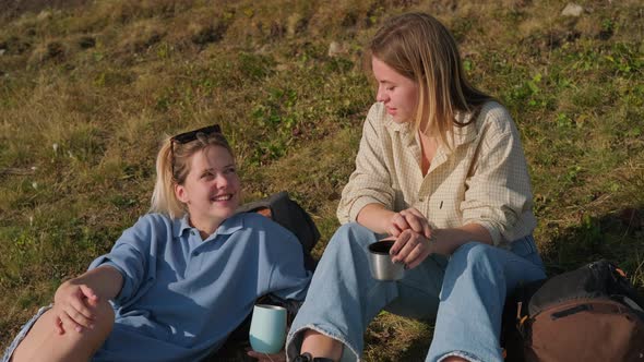 Girls Backpackers Talking Over a Cup of Tea During the Hiking Trip alt
