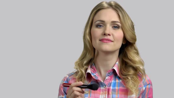 Portrait of Young Blond Woman Doing Makeup Using Brush alt
