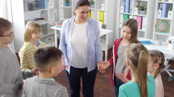 Woman and Six Kids Playing Funny Game in Circle Together alt
